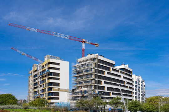 Modern apartment buildings under construction with cranes in Madrid, Spain
