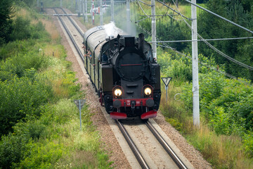 Historic TKt48 steam locomotive pulling a retro passenger train on the railway tracks near Chabowka, Poland © lumofoto