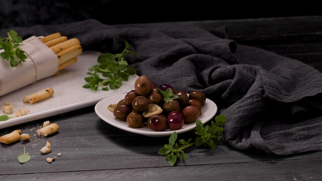Marinated Olives and Bread Sticks on a Dark Wooden Table