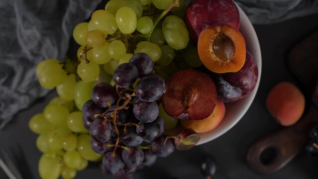 Fresh Fruit Still Life with Grapes, Plums, and Apricots in a White Bowl