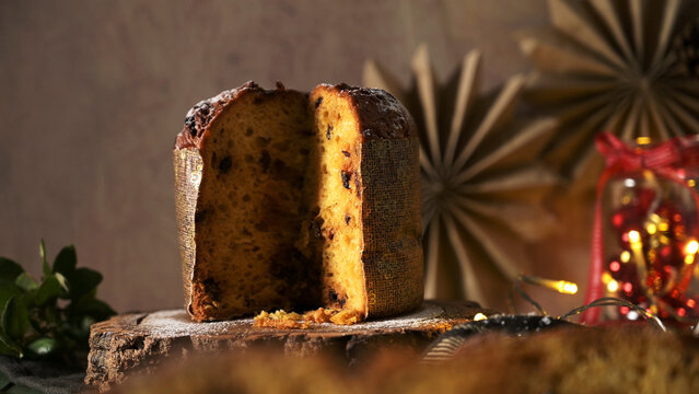 Sliced panettone cake on a rustic wooden stand with festive holiday decorations