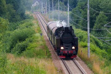 Historic TKt48 steam locomotive pulling a retro passenger train on the railway tracks near Chabowka, Poland © lumofoto