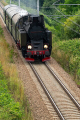 Historic TKt48 steam locomotive pulling a retro passenger train on the railway tracks near Chabowka, Poland © lumofoto