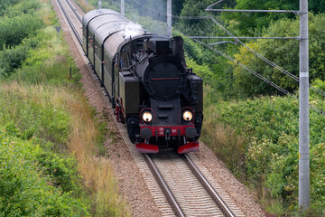 Historic TKt48 steam locomotive pulling a retro passenger train on the railway tracks near Chabowka, Poland © lumofoto