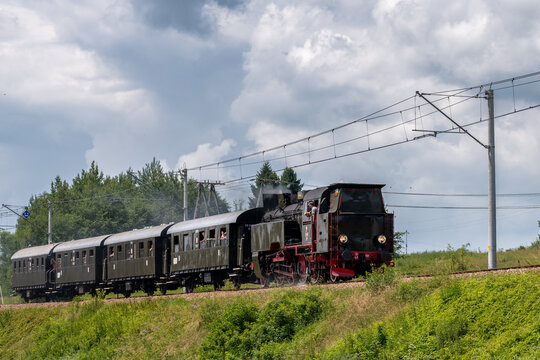 Historic TKt48 steam locomotive pulling a retro passenger train on the railway tracks near Chabowka, Poland