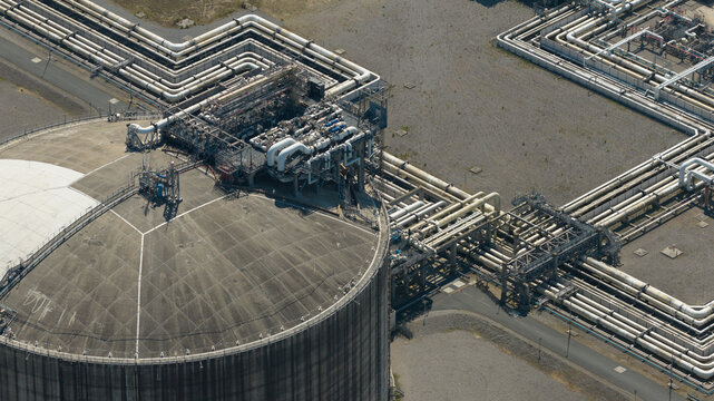 Aerial view of Dunkirk LNG Terminal with large storage tank and complex piping infrastructure in Loon-Plage, Hauts-de-France, France.
