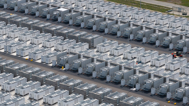 Aerial view of the large cooling tower at the battery energy storage system site, surrounded by rows of white battery containers in Vilvoorde, Vlaanderen, Belgium.