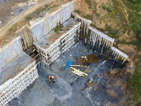Aerial view of a deep construction excavation pit with concrete retaining walls, soil, pipes, and an excavator in Istanbul, Istanbul, Turkiye.