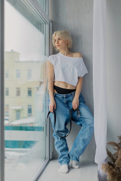 Beautiful woman posing on a large window in a photo studio