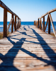 Fototapeta premium Wooden pier leading to the ocean with shadow patterns on the planks