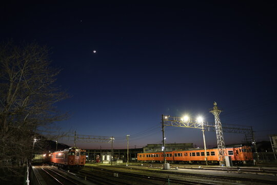 三日月が照らす夜の車両基地と留置されるレトロな気動車