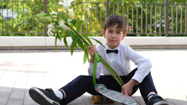 Schoolboy sitting with skateboard and flowers, balancing playful freedom with the nervous formality of a school day
