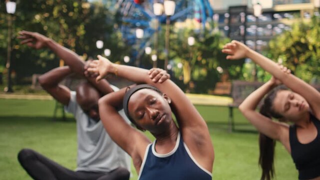 Yoga trainer demonstrates raised arms side stretch and deep breathing as friends follow on mats in park, supporting mobility and guided meditation for wellness.