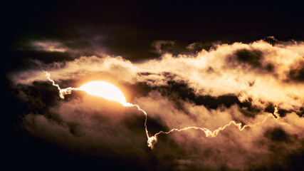 Dramatic sunset sky background with the glowing sun and drifting clouds in vibrant, surreal colors © lumofoto