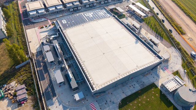 Aerial view of Microsoft Data Center MIL01 MIL02 featuring a large industrial building with solar panels, adjacent parking areas, and surrounding infrastructure in Caleppio, Lombardia, Italy.