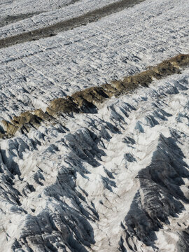 Aerial view of the Aletsch Glacier showing deep crevasses, ice formations, and rocky moraine deposits in the Swiss Alps, Fieschertal, Valais, Switzerland.