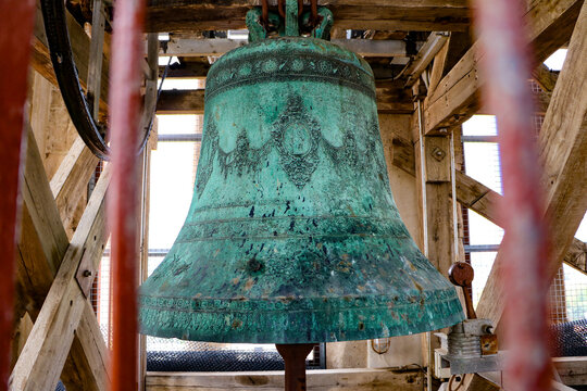 View of an ornate, oxidized bronze bell with intricate relief carvings housed within the wooden framework of the Hvar Cathedral bell tower in Hvar, Split-Dalmatia County, Croatia.