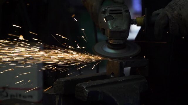 Close-up of skilled welder joining steel metal plates with bright glowing sparks in workshop