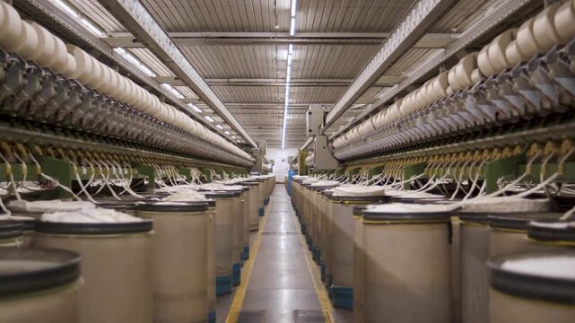 Macro detail of cotton threads feeding into modern machinery weaving fabric in textile factory