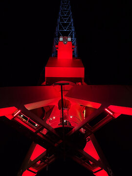 View of the illuminated red crane at Leuvehaven at night, featuring structural steel beams and vibrant lighting against the dark sky in Rotterdam, South Holland, Netherlands.