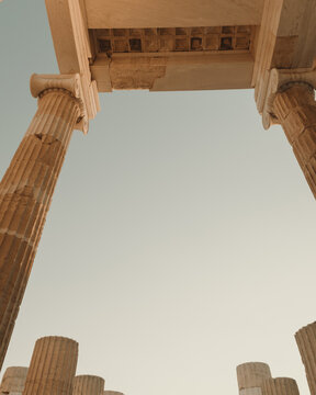 View of the ancient marble columns of the Acropolis under a clear sky in Athens, Greece.