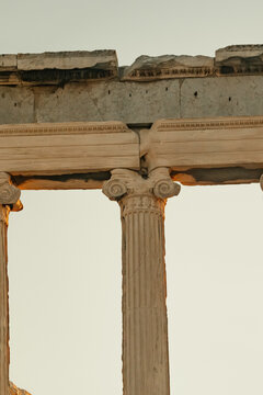 View of Acropolis with ancient marble columns and detailed stone carvings under clear sky in Athens, Greece.