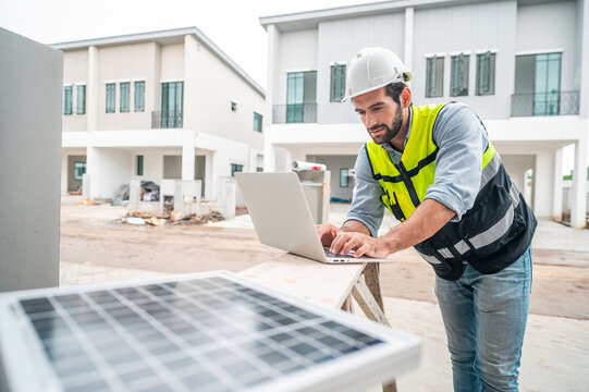 Construction worker engineer using a laptop at a residential construction site with solar panels