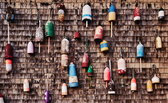 colorful, weathered wooden lobster buoys hanging against a rustic, dark wood shingle wall, Portland, Maine, New England 