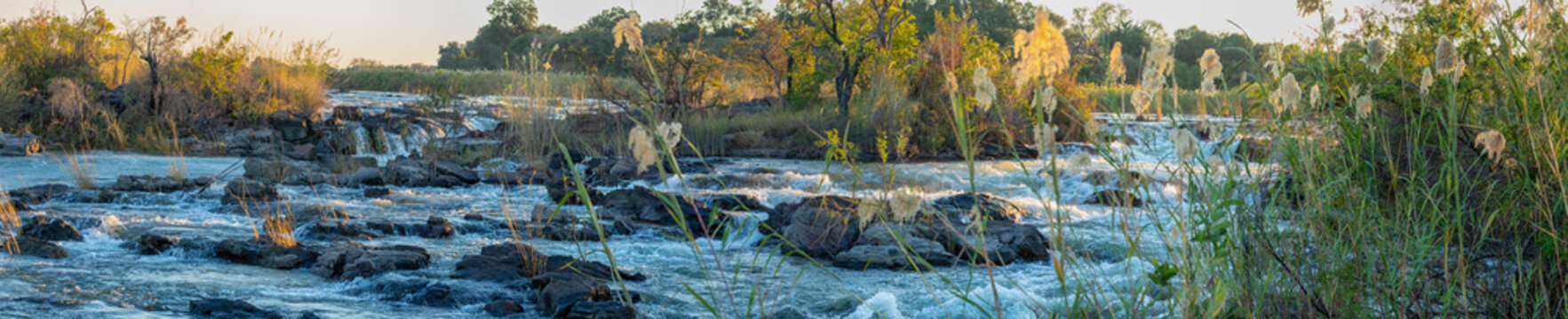 View of the Okavango Delta with flowing water, rocky outcrops, and lush reeds in North-West District, Botswana.