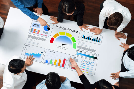 A group of professionals collaborates over a risk dashboard, analyzing visual data presentations and performance metrics to inform decision-making and strategy. Nascent