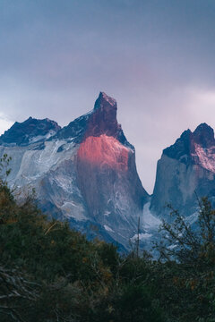 View of Cordillera del Paine peaks illuminated by the golden hour light with rugged rock faces and snowy slopes in Torres de Paine, Magallanes and Chilean Antarctica, Chile.