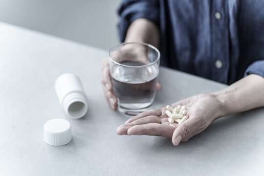 大量の薬を飲む女性の手元