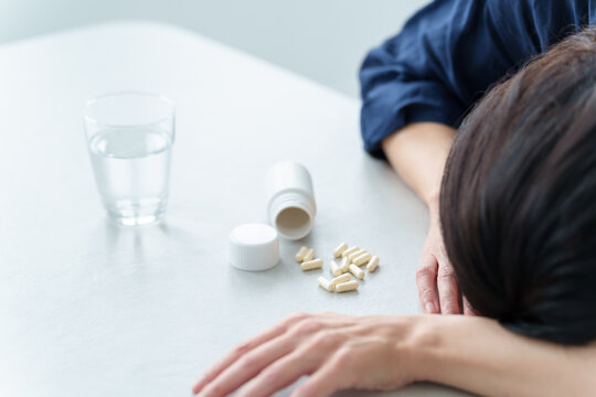 薬を飲んで倒れる女性