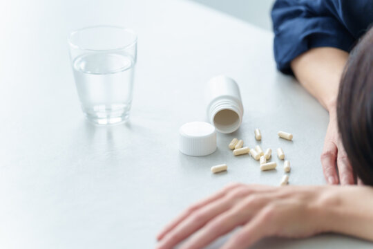 薬を飲んで倒れる女性