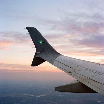 Airplane wing flying high above clouds during glowing sunset twilight