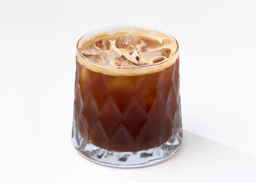 A chilled glass of iced coffee resting on a white background.