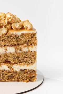 A delicious layered cake topped with popcorn rests on a circular base against a clean background.