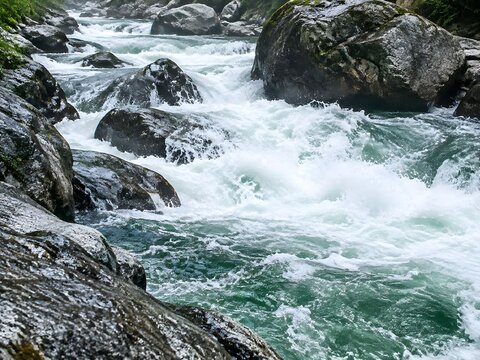 Whitewater rapids rushing between boulders with aerated churning foam and granite