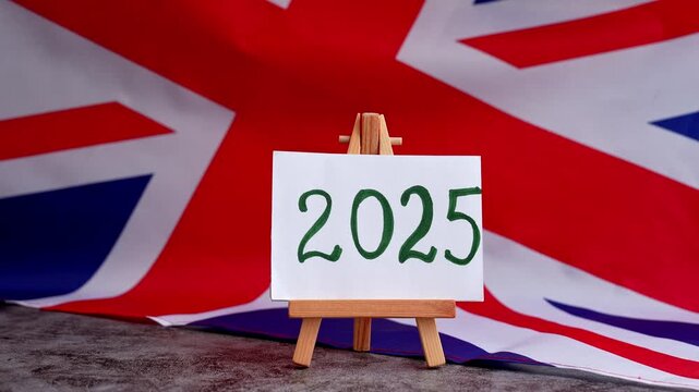 Paper note with text 2025 on National symbol of Great Britain. British wave the UK silky flag background. Concept of financial outlook planning, new year annual report