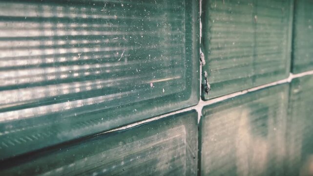 Vintage glass block wall texture with retro green color grading and sliding camera motion for industrial architecture, interior design, and abstract background visuals.