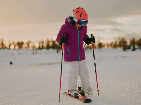 Young girl skiing downhill on a groomed piste at sunset in Norway