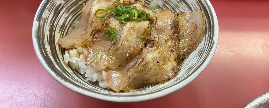 刷毛目模様の器に盛られた炙りチャーシューとねぎをのせた白飯のチャーシュー丼