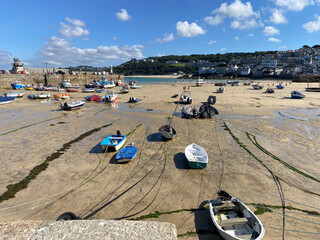 Small boats stranded on muddy seabed at low tide, harbour with lighthouse and wooded hills, St Ives, England, United Kingdom © Alexander Will