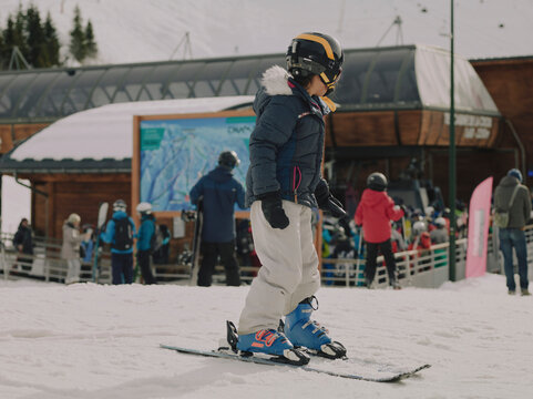 Child taking a ski lesson, gliding down a gentle snowy slope in Chamrousse