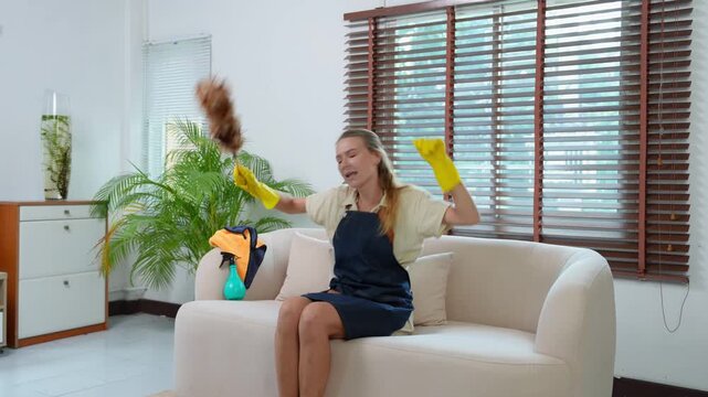Happy housekeeper singing and dancing on sofa