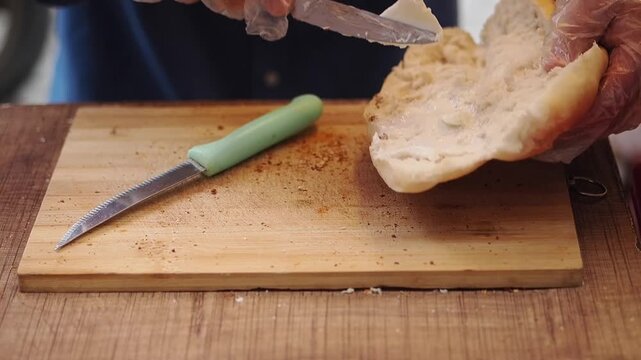 Chef Spreading Sauce on Bread Roll in Kitchen