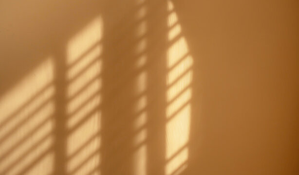 Warm sunlight casting soft window shadows on a beige wall. Creating a minimalist abstract background with natural light, texture and copy space.