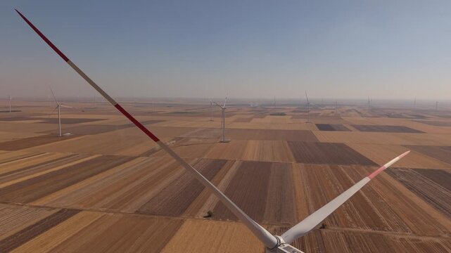 Wind Turbine Blades Framing a Vast Agricultural Plain from Above