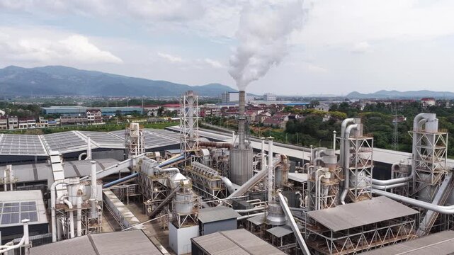 Large industrial factory chimney emitting thick smoke in the park