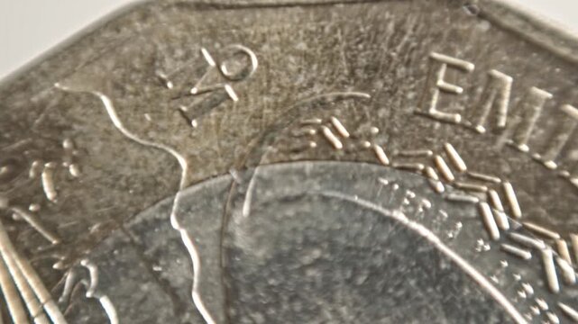 Spinning coin captured in macro close up showing engraved lettering and detailed metallic surface texture. Rotating currency creates an abstract financial and monetary visual.